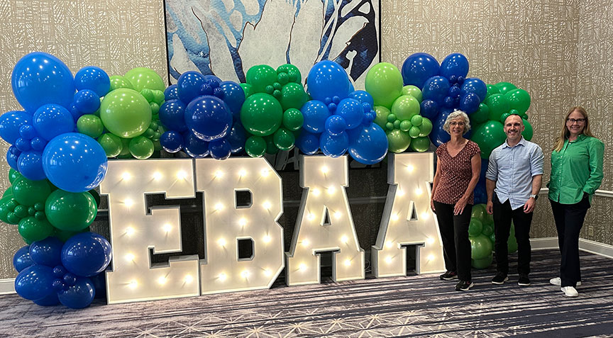 Lynn Chris and Jodi beside balloons and lit EBAA sign